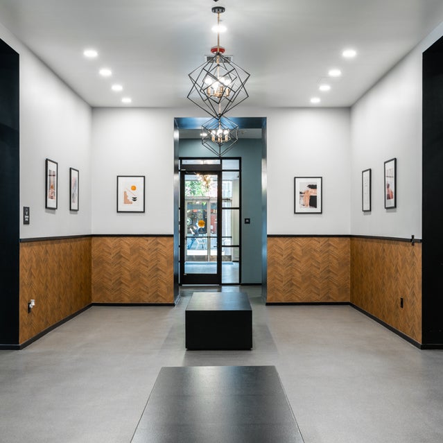 Domain Oakland Apartments - art gallery with seating and pathway to package room