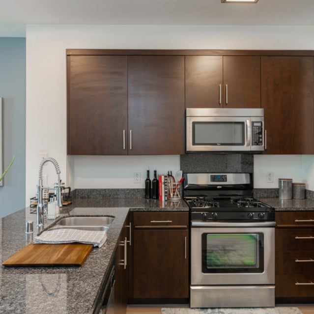 Domain Oakland Apartments - kitchen with stainless steel appliances and wooden cabinetry