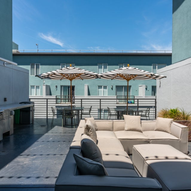 Domain Oakland Apartments - sky lounge with sofa area and dining tables with umbrellas